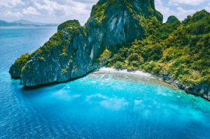 El Nido, Palawan. Aerial drone view of tropical Entalula Island. Huge steep rocks cliffs mountains with blue bay and beautiful intact coral reef. Island hopping tour trip. El Nido, Palawan. Aerial drone view of tropical Entalula Island. Huge steep rocks cliffs mountains with blue bay and beautiful intact coral reef. Island hopping tour trip.